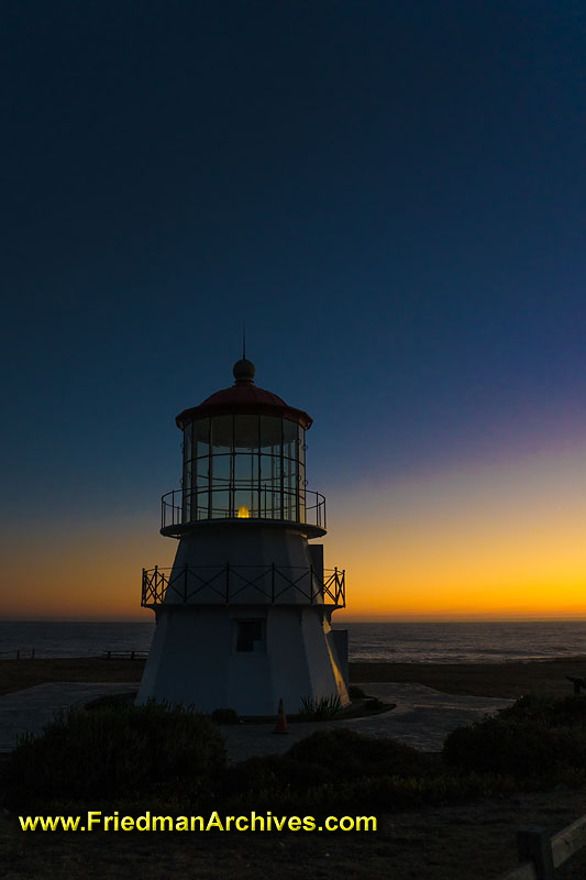 Lighthouse,sunset,sunrise,dusk,dawn,orange,blue,shadow,short,maritime,ocean,shore,